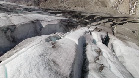 Glacier-crevasses-surfaces-with-cracks-and-mud,-Melting-glacier-water-streams-through-mountains