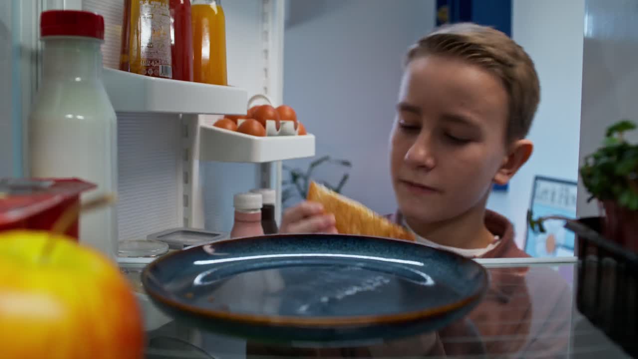 niño comiendo sándwich del refrigerador