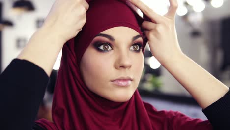 gorgeous caucasian looking girl at her 20's puts on purple chiffon hijab or traditional arabic head cover.