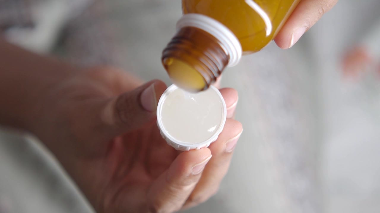 Persona che versa una medicina liquida in un misurino