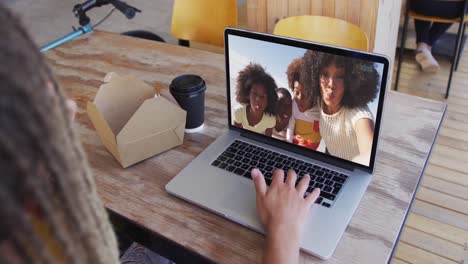 Frau-Isst-Einen-Snack,-Während-Sie-Im-Café-Einen-Videoanruf-Auf-Dem-Laptop-Führt