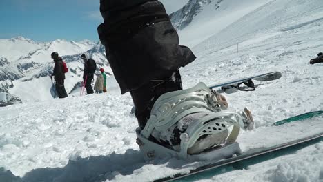 snowboarder strapping in. closing snowboard bindings