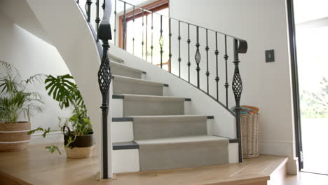 Carpeted-spiral-staircase-and-pants-in-light-hallway-of-luxury-home,-copy-space,-slow-motion