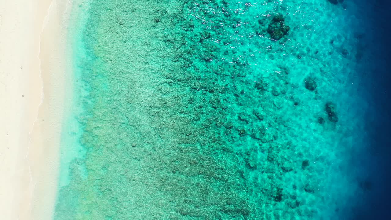 Blue turquoise sea on shoreline full of coral reefs and rocks underwater, near sandy beach of tropical island in Caribbean