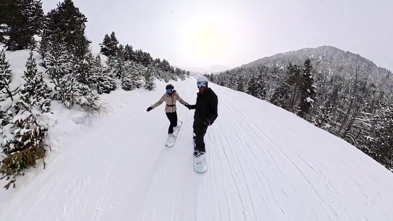 Coppia che fa snowboard insieme su un pendio montano innevato