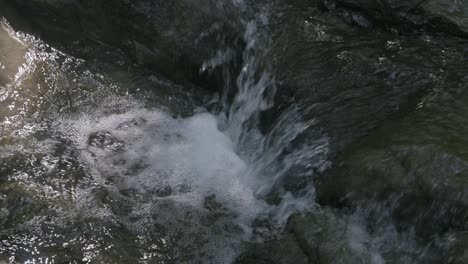 Cerrar-Imágenes-En-Cámara-Lenta-De-Una-Pequeña-Cascada-Saliendo-De-Una-Roca-En-Un-Arroyo