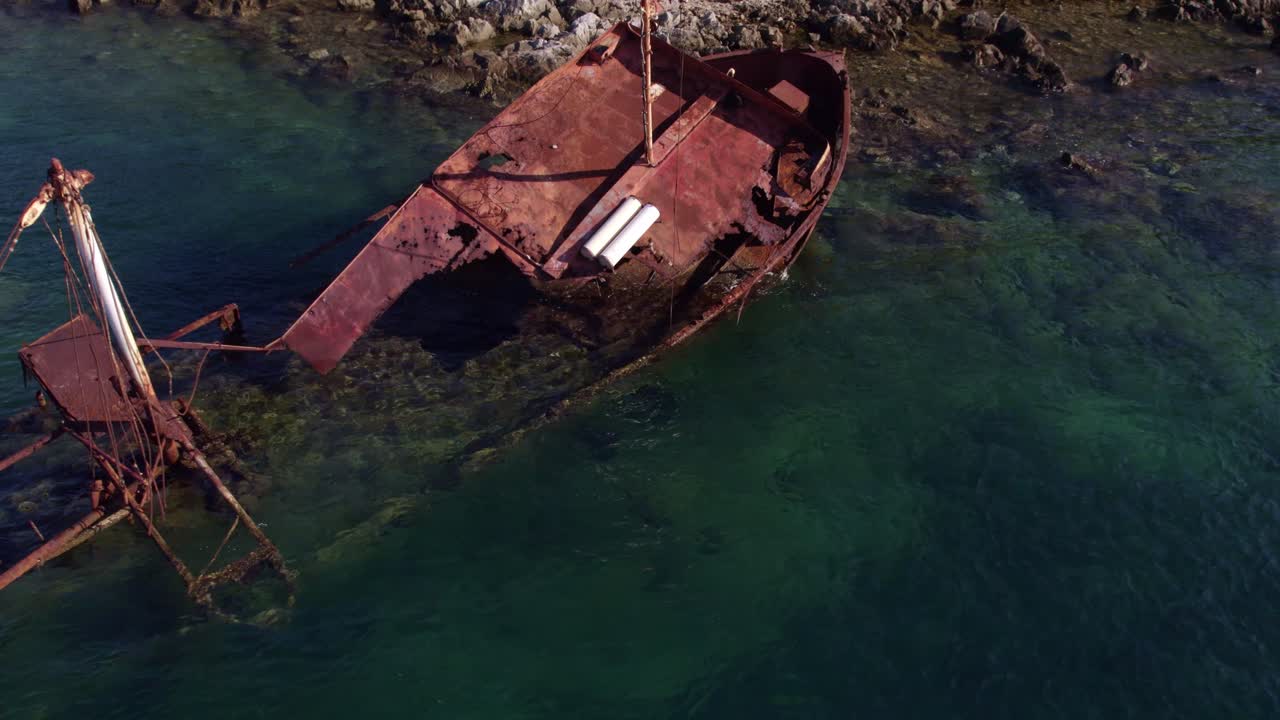 Toma aérea de aguas turquesas con un naufragio en la Bahía de Kotor, Montenegro.