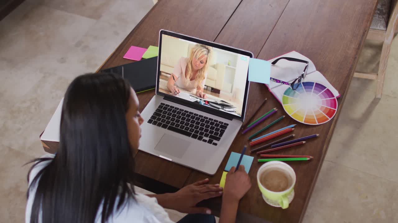 maestra caucásica usando computadora en videollamada con una estudiante, escribiendo