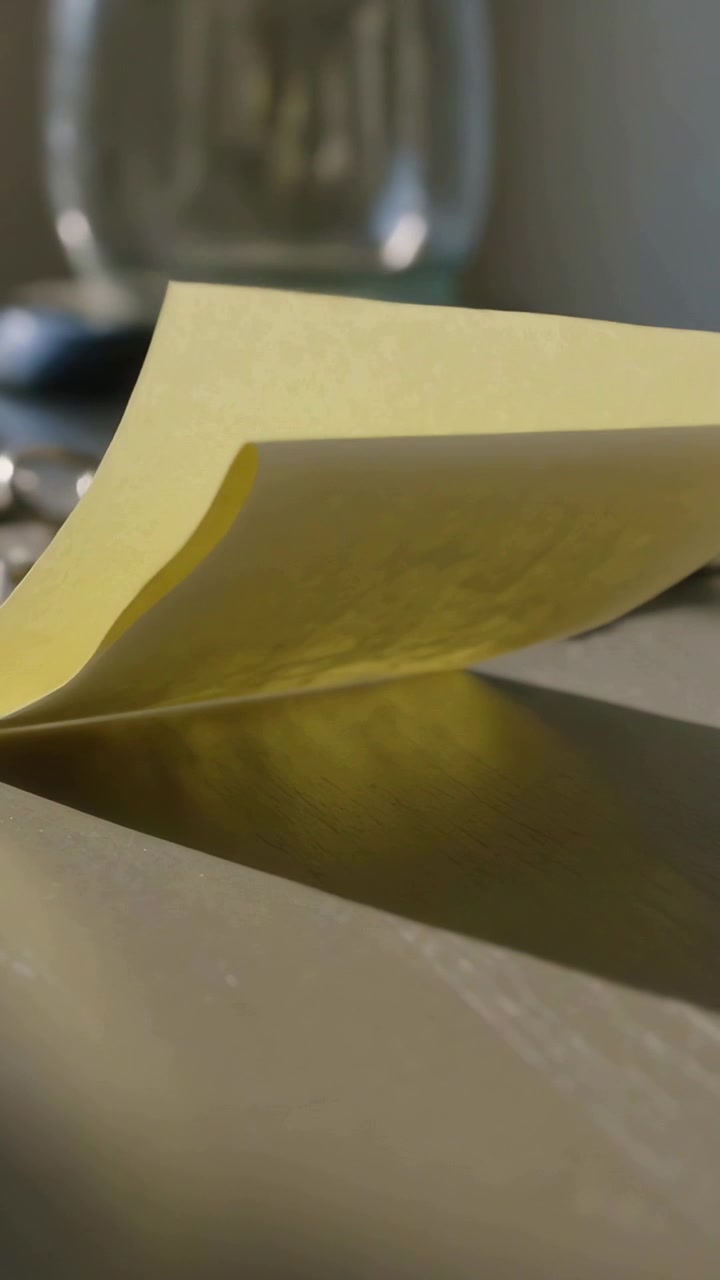 Vertical video: Curling and flipping sticky note marked after camera move on table with keys, lamp