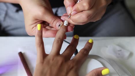 Anonymous-beautician-applying-lacquer-on-female-client-nails