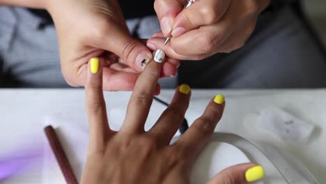 anonymous beautician applying lacquer on female client nails