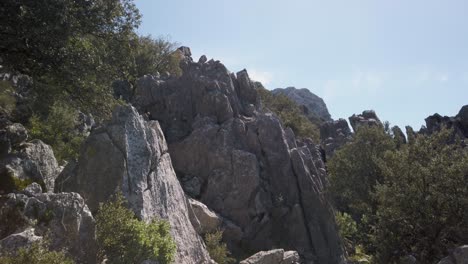 Trail-by-jagged-rocks-on-mountain-in-Grazalema-Natural-Park,-Spain,-TILT-UP