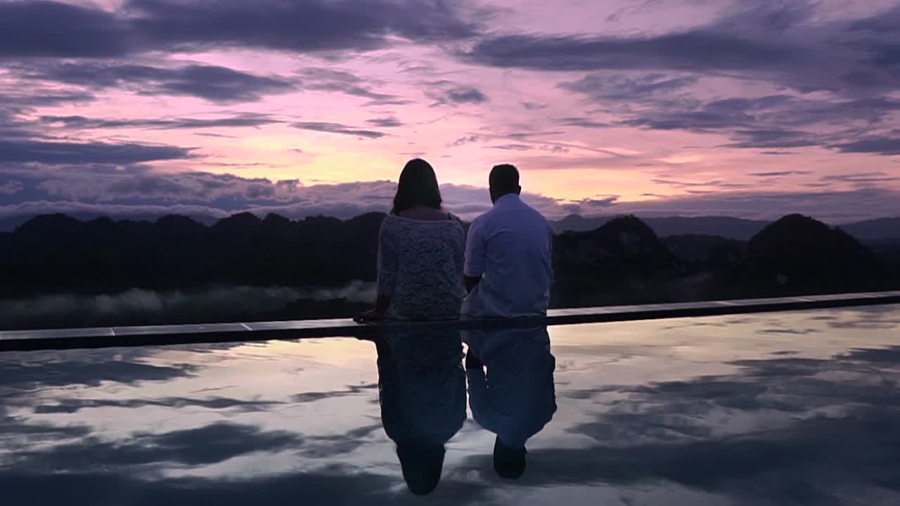 수영장 옆에 앉아 일출을 즐기는 로맨틱 커플