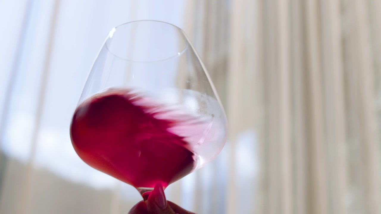 Vista ravvicinata di una donna che tiene in mano un bicchiere di vino rosso. Primo piano