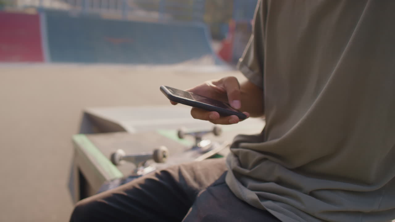 Young Man in Headphones Using Mobile Phone in Skatepark