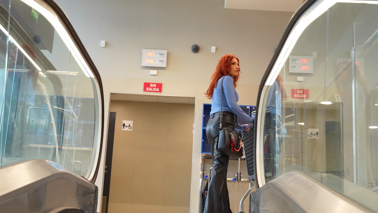 Frau kommt im Supermarkt an und schiebt Einkaufswagen auf Rolltreppe