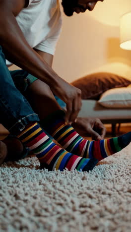 man putting on colorful striped socks