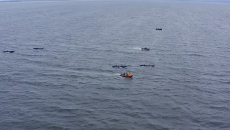 Drohnen-Dolly-über-Dem-Currach-Boot-Im-Offenen-Meerwasser,-Gefolgt-Von-Sicherheitsbooten