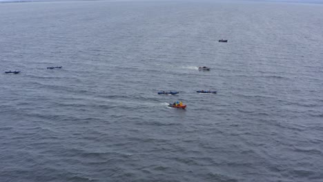 drone dolly por encima del barco currach en aguas abiertas del océano con botes de seguridad siguiendo