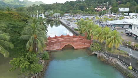 small arch bridge on a river in langkawi with mountain and jungle at background