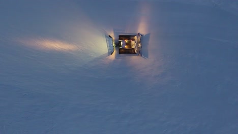 aerial drone shot of a snow groomer in action during sunset in the french alps.