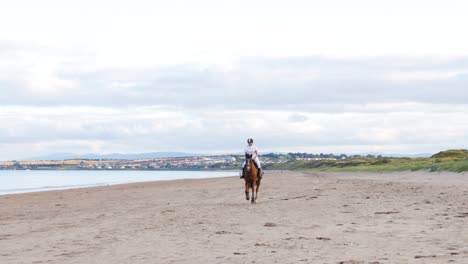 Ein-Schönes-Mädchen-Mit-Langen-Haaren-Reitet-Abends-In-Donabate,-Irland,-Auf-Ihrem-Pferd-Am-Strand