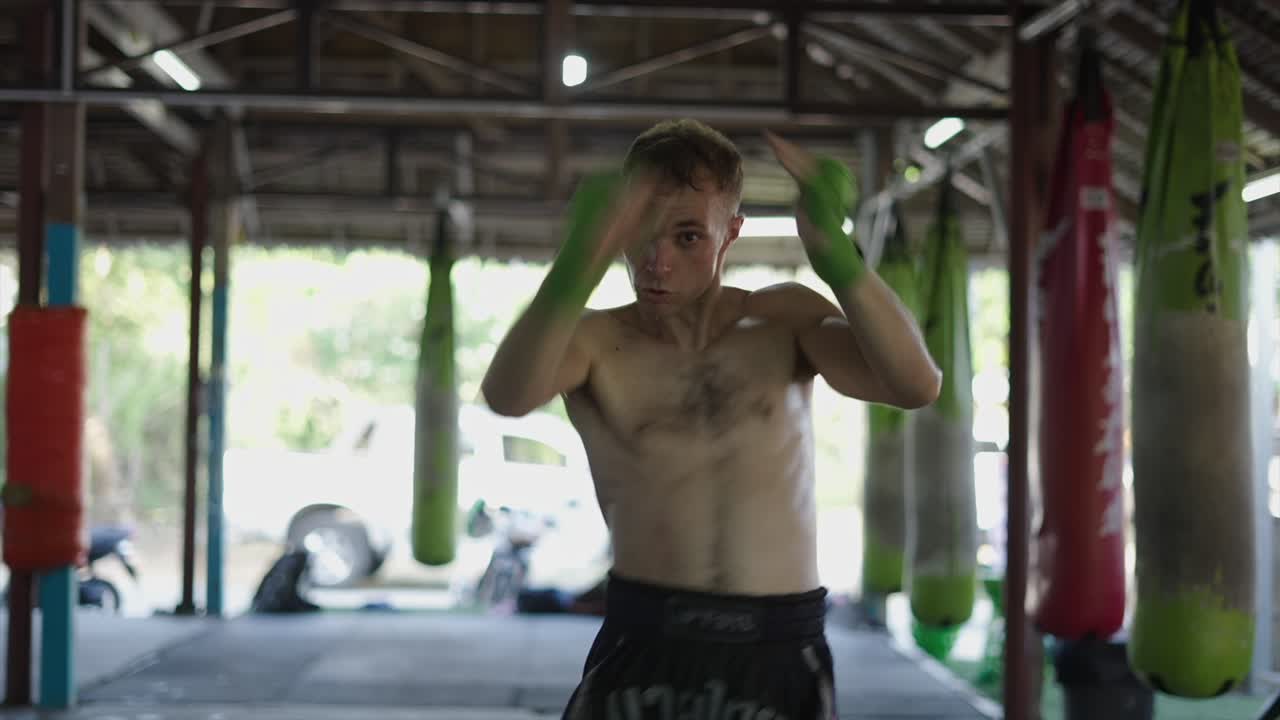 A man intensely training martial arts in a gym with punching bags