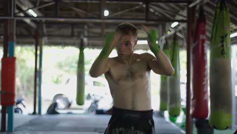 a man intensely training martial arts in a gym with punching bags