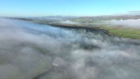 Static-hovering-shot-above-thick-mist-drifting-across-countryside-landscape-at-dawn-in-winter