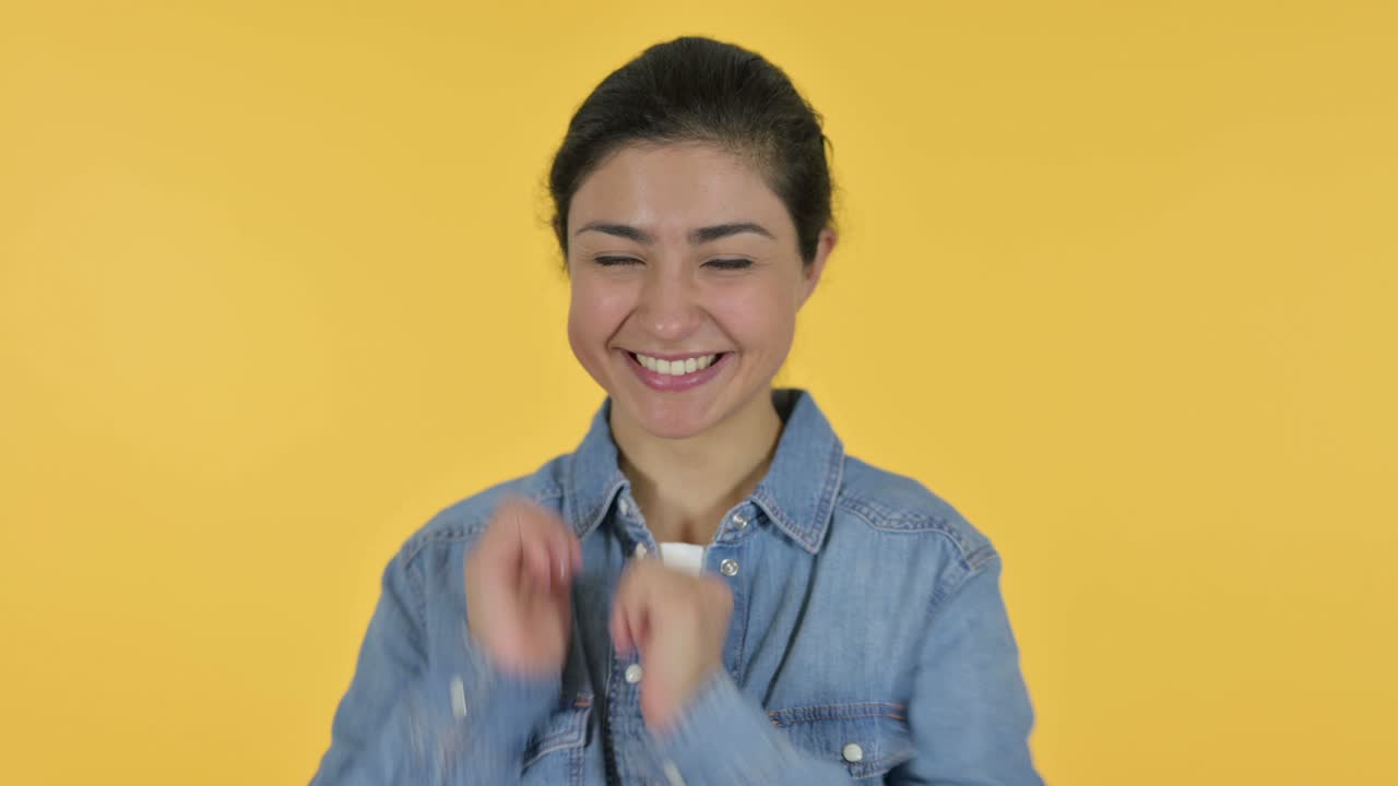 긍정적 인 젊은 인도 여성 박수, 노란색 배경