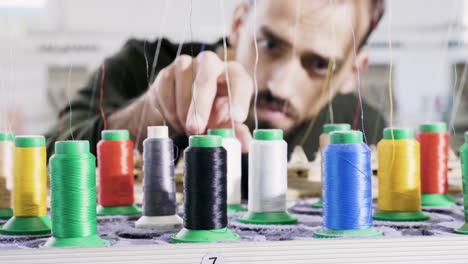 man in a fabric factory checking the sewing thread