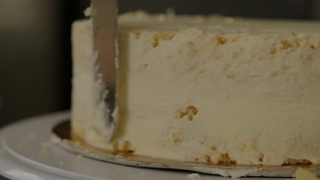 close-up of frosting the sides of a vanilla sponge cake