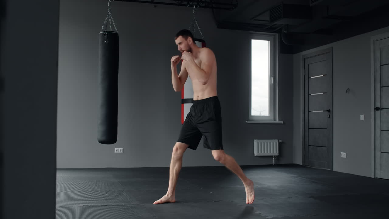 Man practicing Muay Thai kicks and punches in a gym