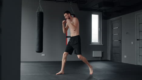 man practicing muay thai kicks and punches in a gym