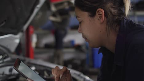 mecánica usando una tableta digital e inspeccionando el automóvil en una estación de servicio de automóviles