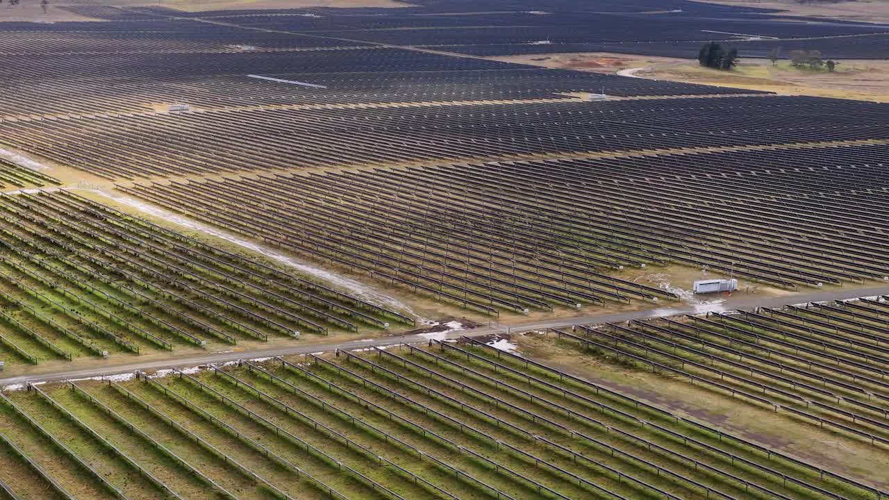 Expansive solar panel array viewed from above, gradual drone movement, natural daylight, rural landscape
