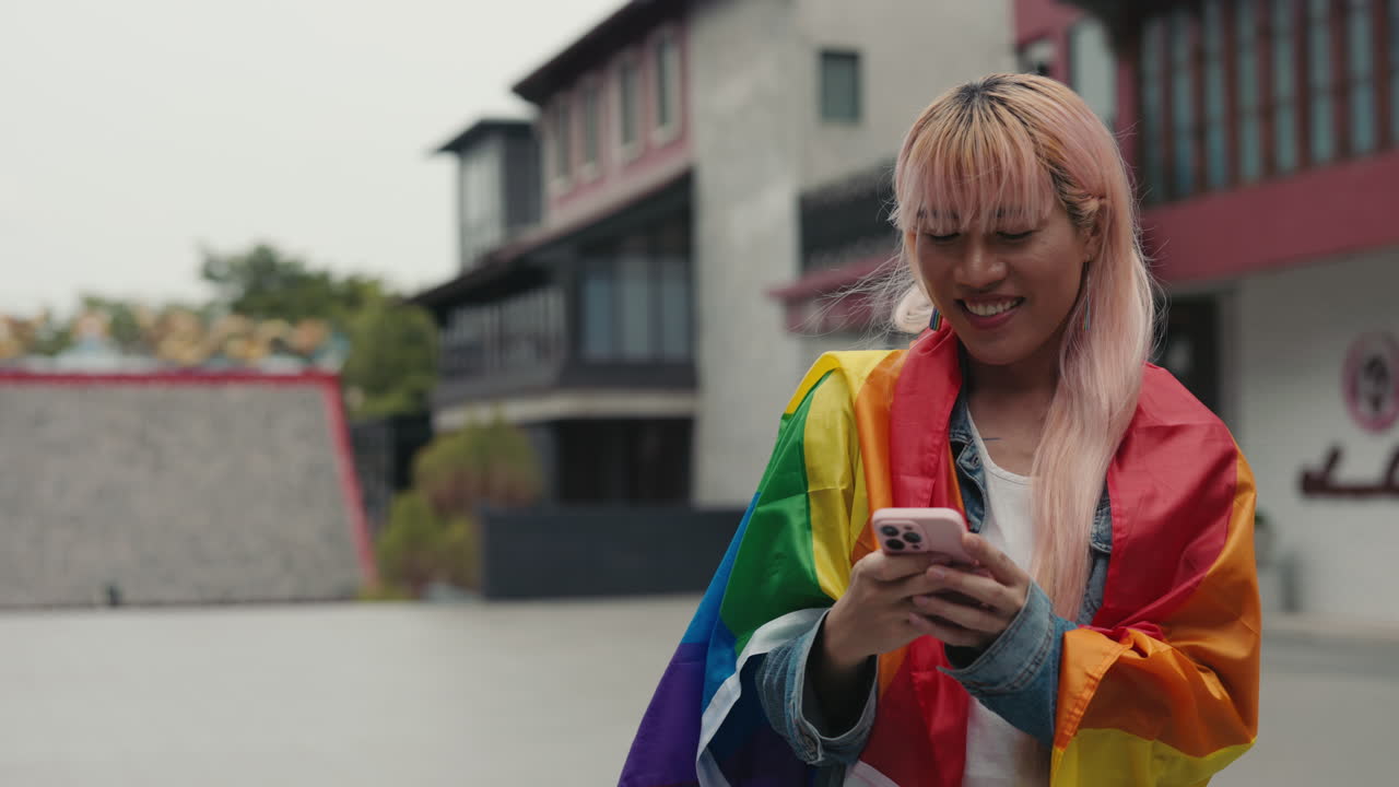 Woman using phone wrapped in pride flag