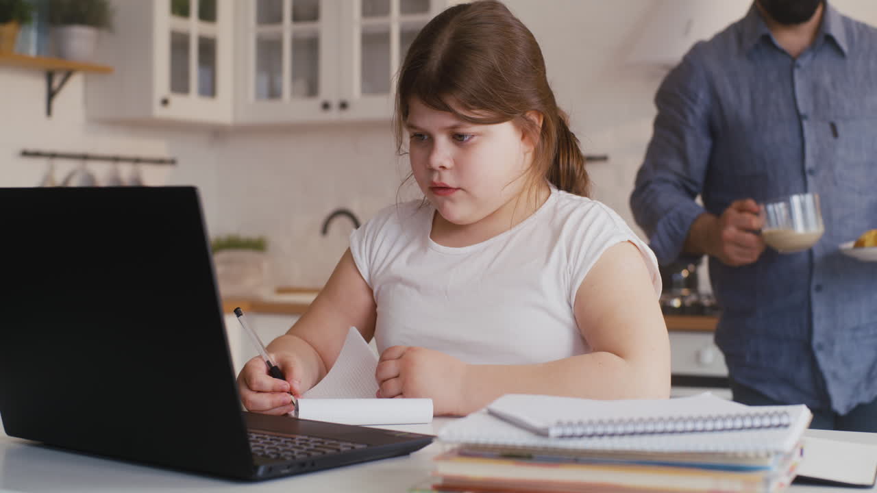 Girl Doing Online Homework with Dad in Kitchen