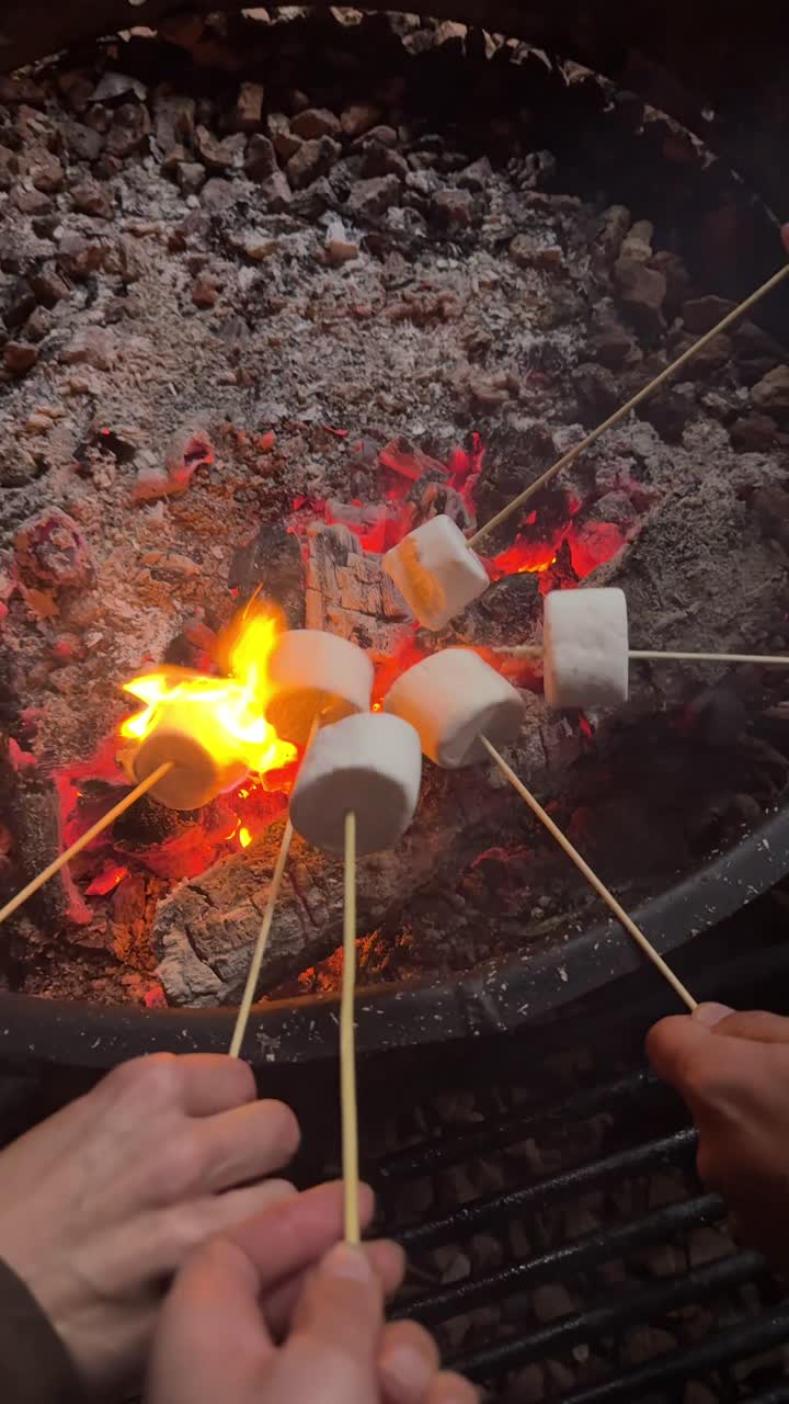 Mani che arrostiscono marshmallow su un accogliente falò di notte