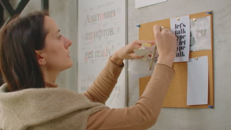 a woman designer standing at the wall attaches her ideas to the wall color selection and coloristics. choosing a color and preparing to create a design and color solution.