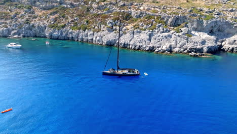 aerial view of a black sailboat in turquoise water, sunny day in rhodes, greece
