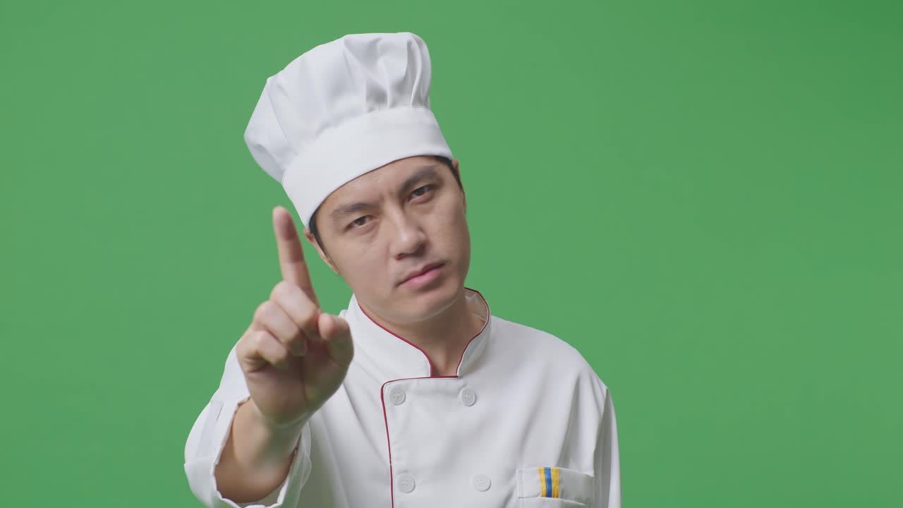 Close Up Of Asian Man Chef Pointing At You And Disapproving With No Index Finger Sign In The Green Screen Background Studio