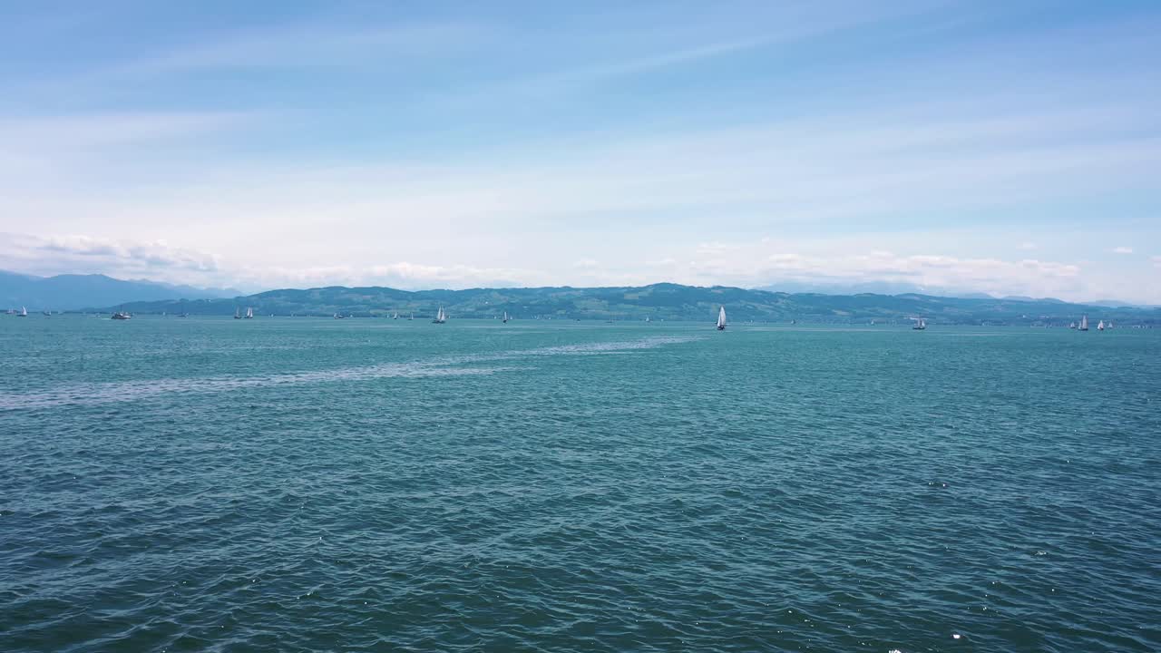 독일 콘스탄츠 호수에서 범선과 산이 내려다보이는 바다 위로 빠르게 날아가는 드론