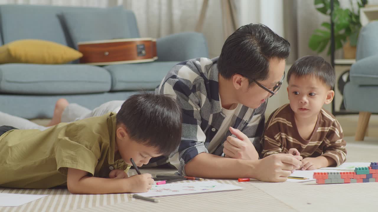 플라스틱 장난감 벽돌로 방 바닥에 누워있는 아시아 아버지와 아들의 근접 사진.