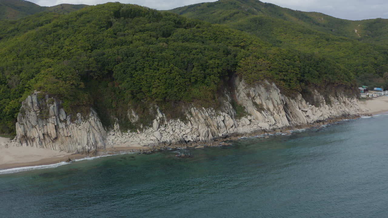 꼭대기에 푸른 숲 언덕이 있는 가파른 절벽 바다 해안의 조감도