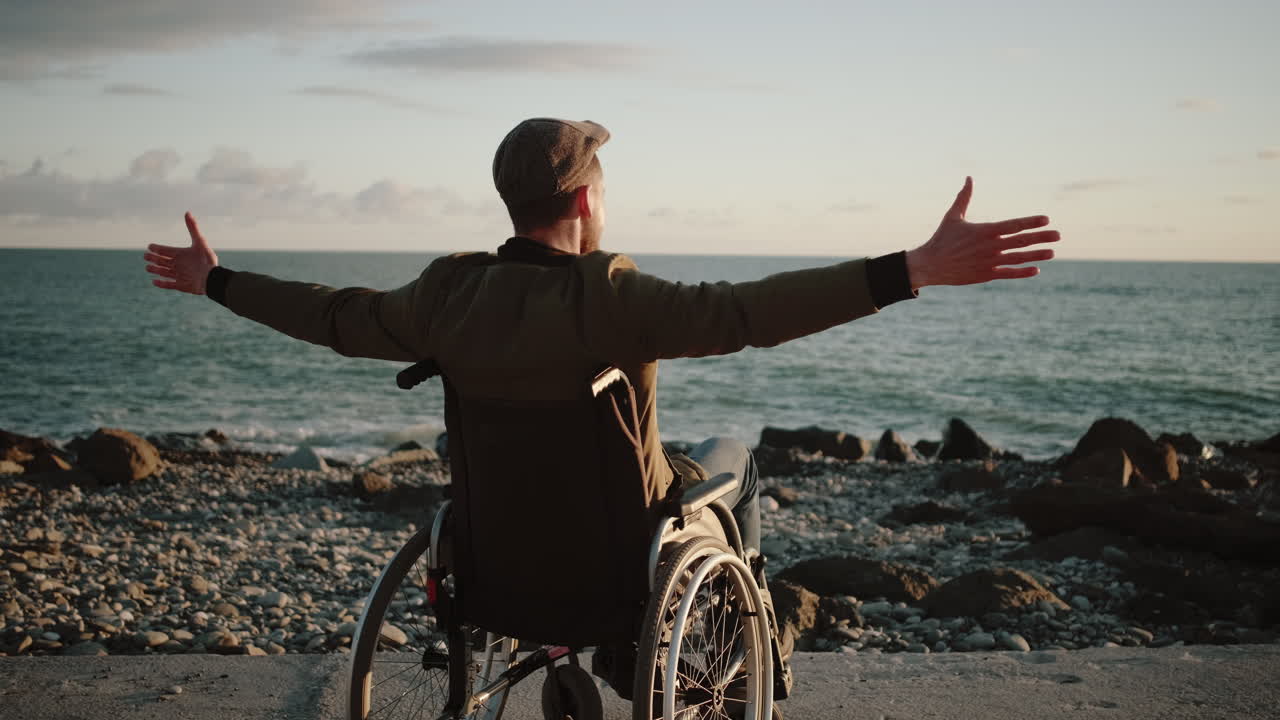 hombre discapacitado disfrutando de la puesta de sol junto al océano