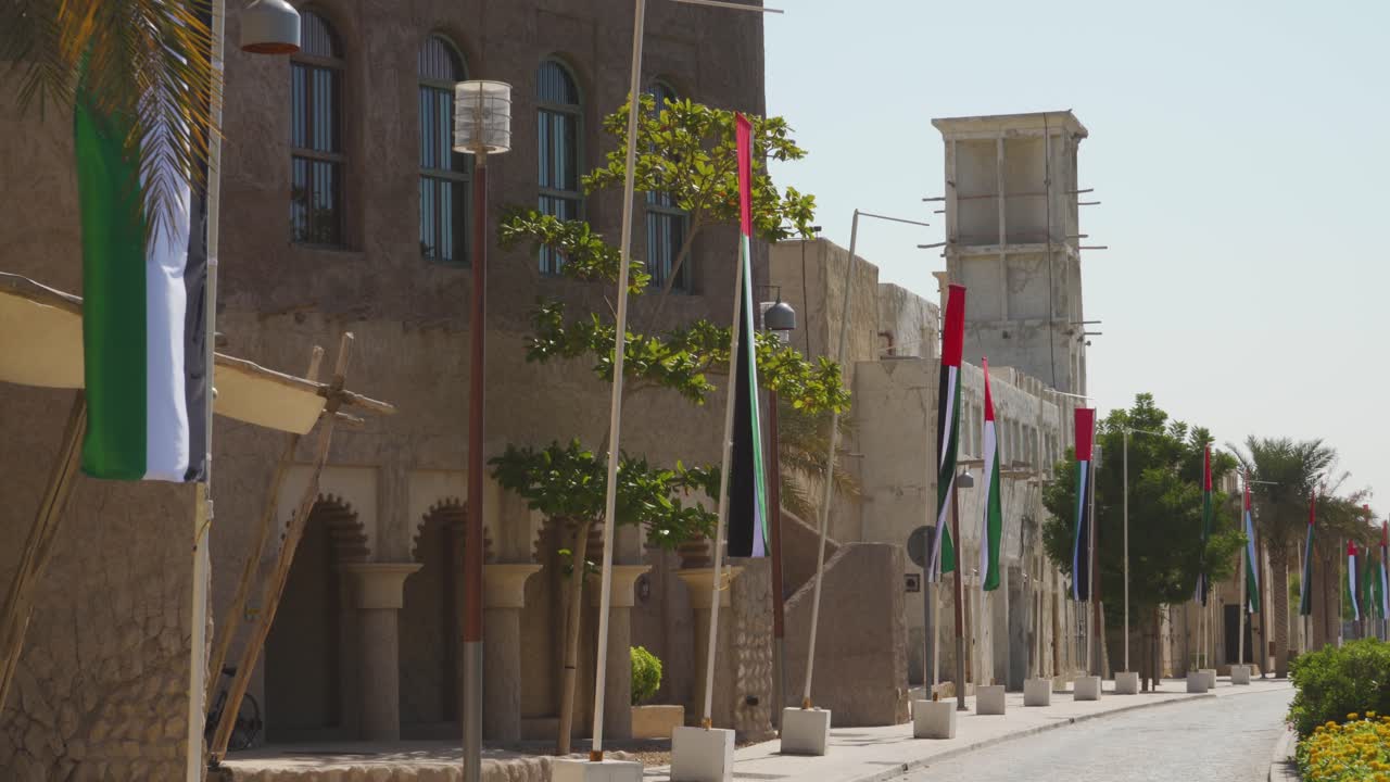 barrio histórico de al fahidi en dubai con edificios antiguos y soporte de bandera enfrente durante el día - plano general