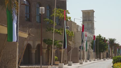 Al-Fahidi-Historisches-Viertel-In-Dubai-Mit-Alten-Gebäuden-Und-Flaggen-Davor-Tagsüber---Breite-Aufnahme