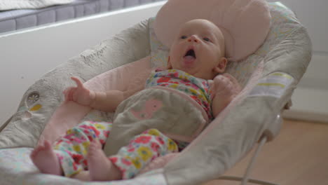 bebé de dos meses en silla de balanceo en casa