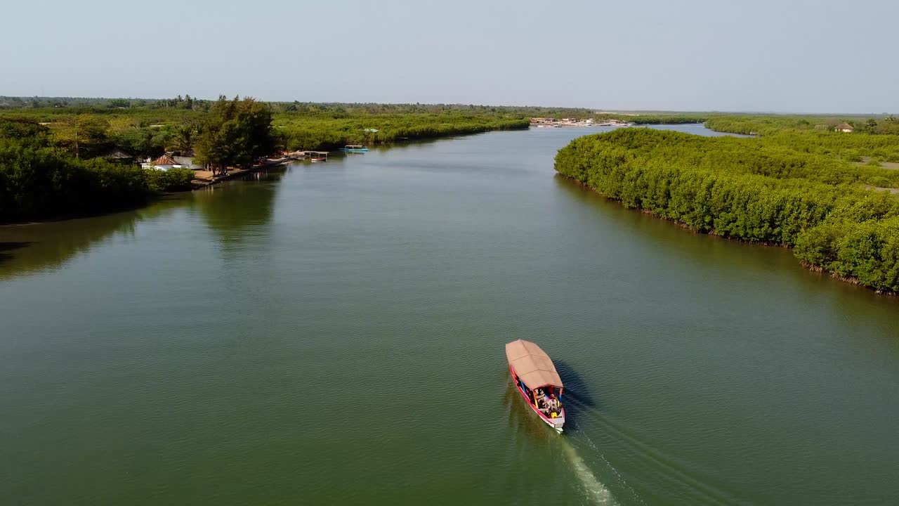 impresionante vista aérea deslizante de un barco turístico local navegando en el río gambia con gaviotas volando en kartong